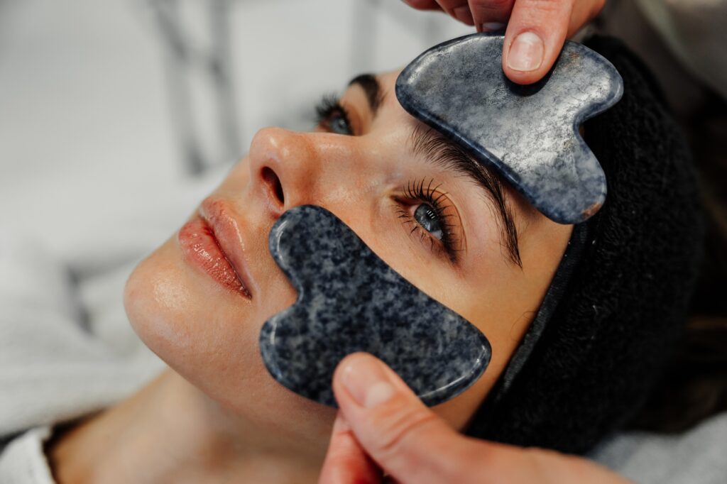 Relaxing facial treatment with gua sha stones at a spa during the day in a calm setting